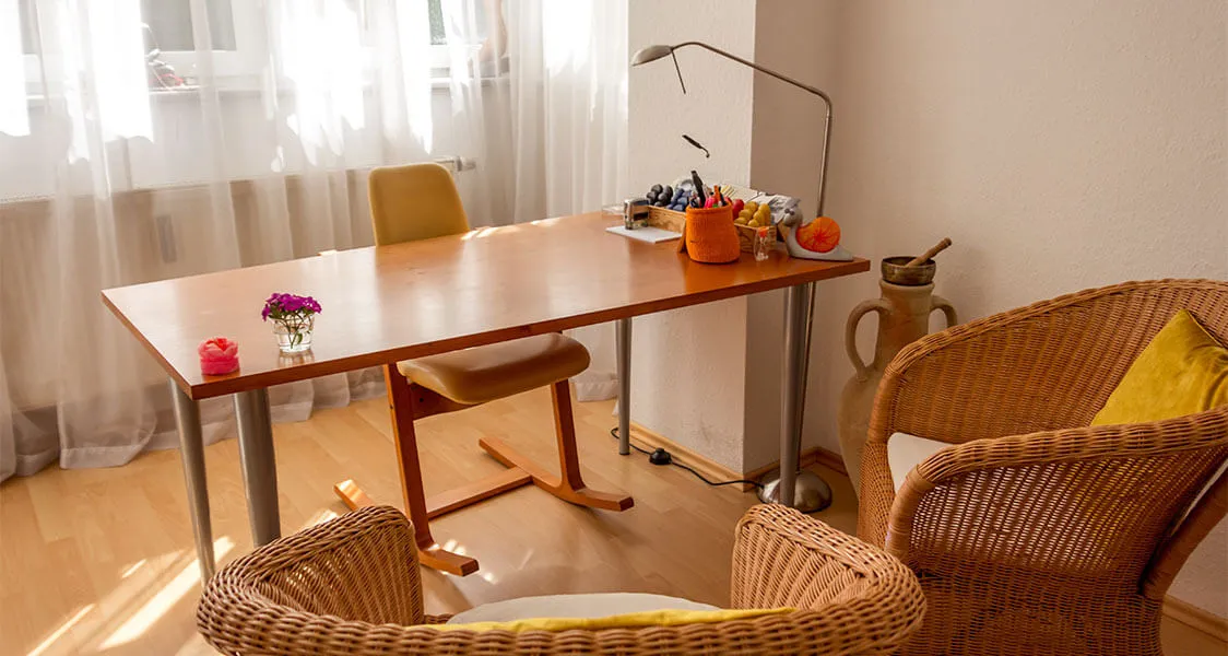 Praxisraum mit Fensteransicht, drei Stühlen und einem Tisch